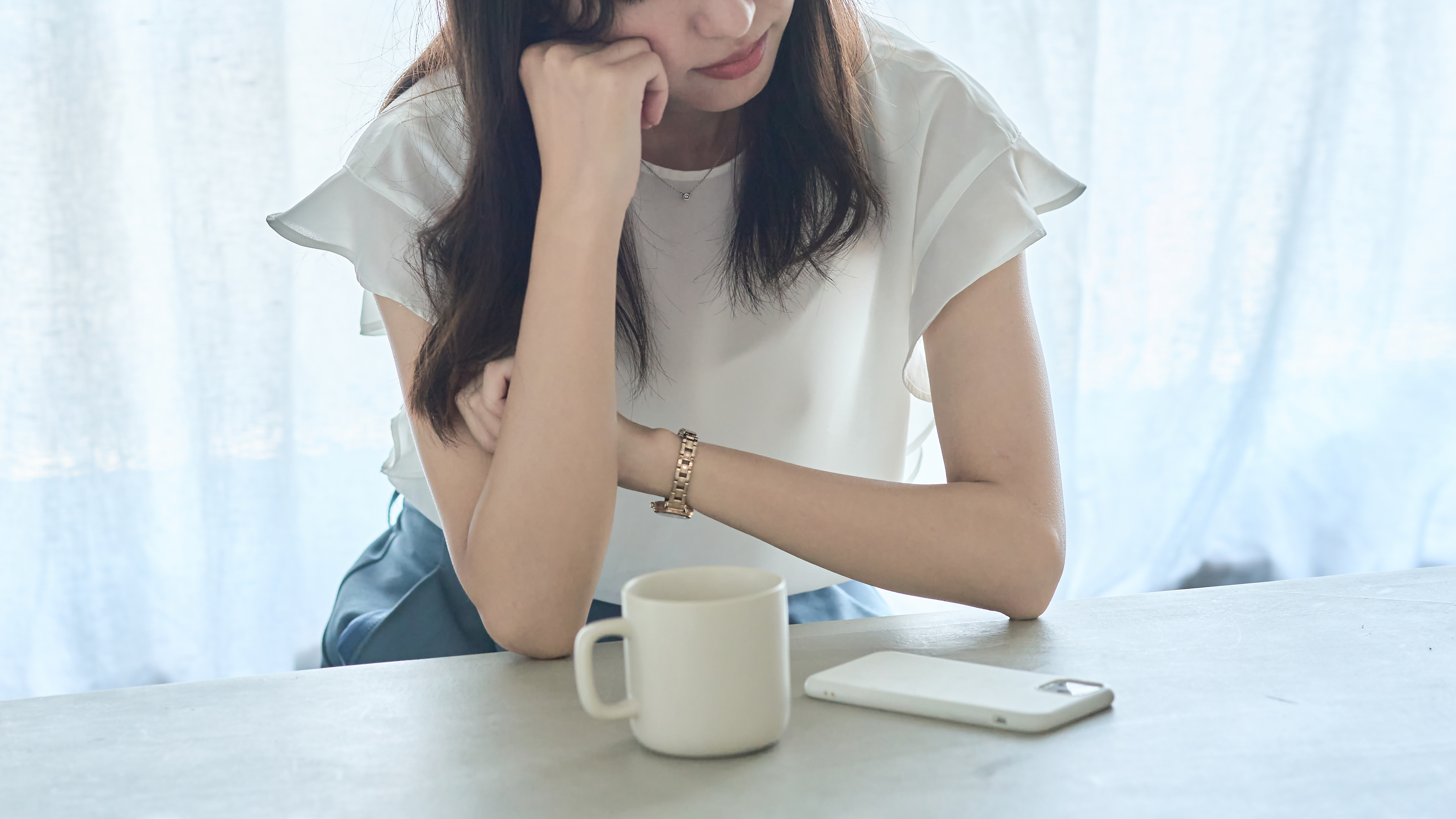 肘をついてため息をつく女性