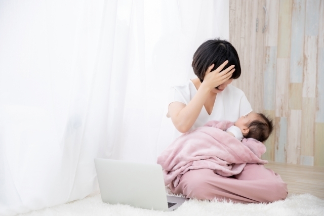 子どもを抱っこしながら家事をする母親